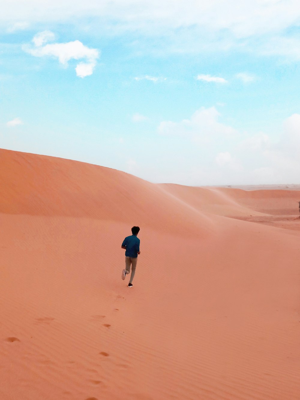 a man walking across a sandy field in the desert