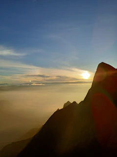 Sunrise casting golden light over jagged alpine peaks with a clear blue sky
