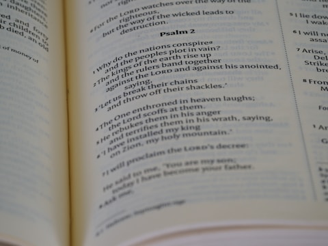 Open book displaying printed text, specifically a passage from a psalm, with a focus on neat typography and verses marked in sequence. The book is laid out on a flat surface with visible binding.