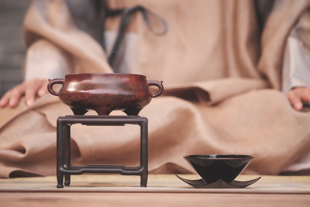 a brown pot sitting on top of a table next to a black bowl