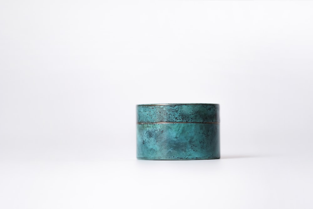 a green metal container sitting on top of a white surface