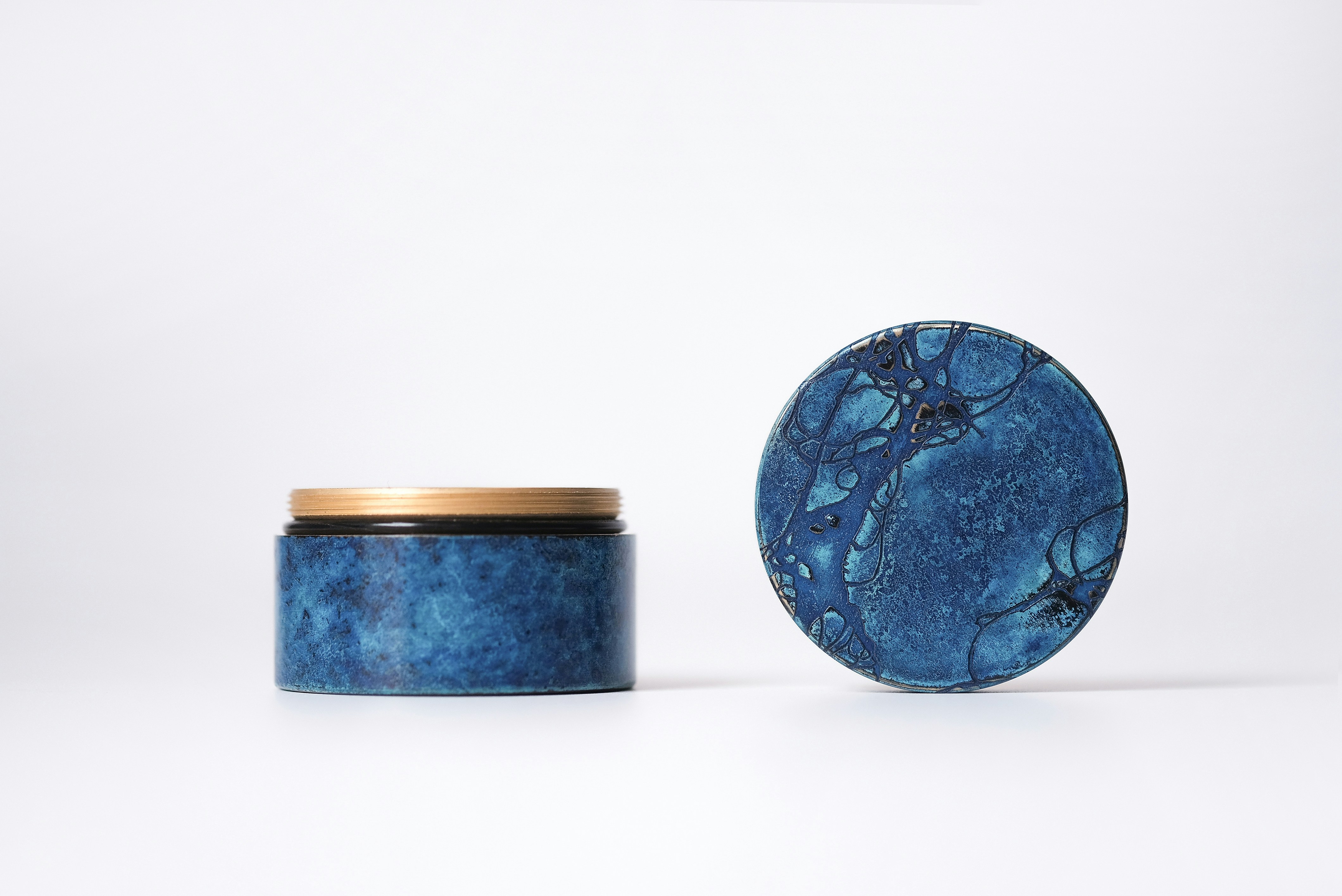 a blue jar with a lid sitting next to a white wall