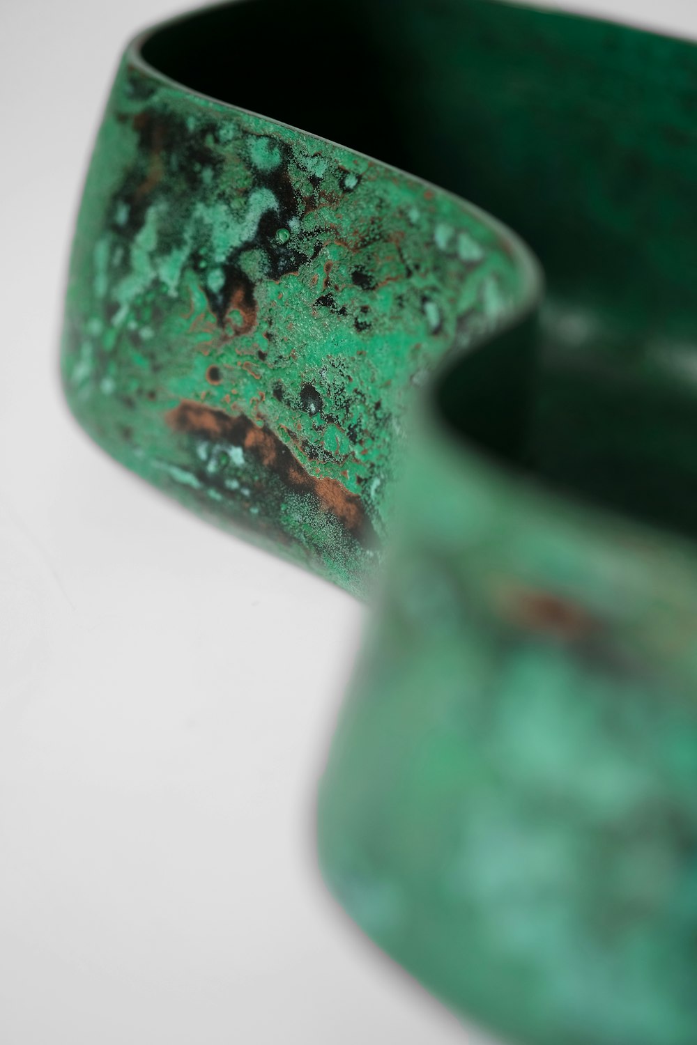 a green vase sitting on top of a white table