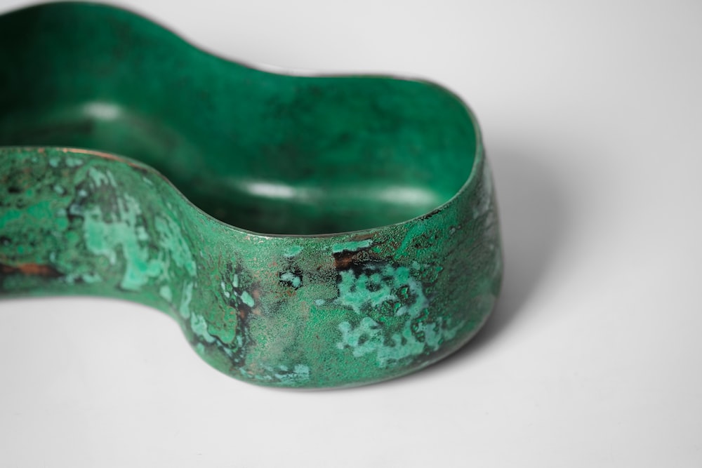 a close up of a green bowl on a white surface