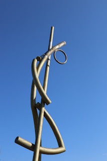 A towering metal sculpture with intricate geometric patterns, set against a clear blue sky.