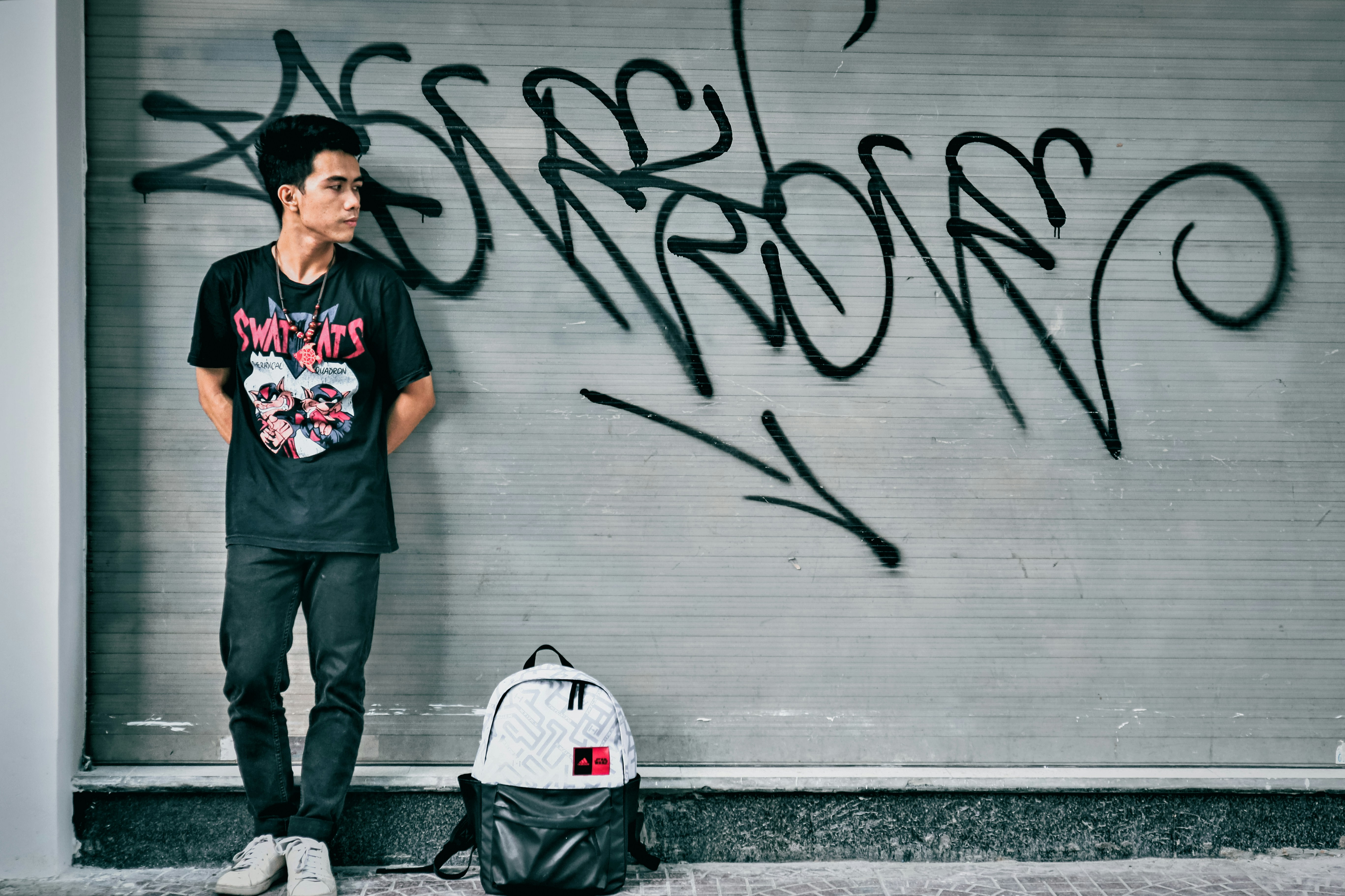 a man standing next to a wall with graffiti on it
