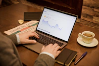 Investor analyzing property market trends on a laptop at a café.