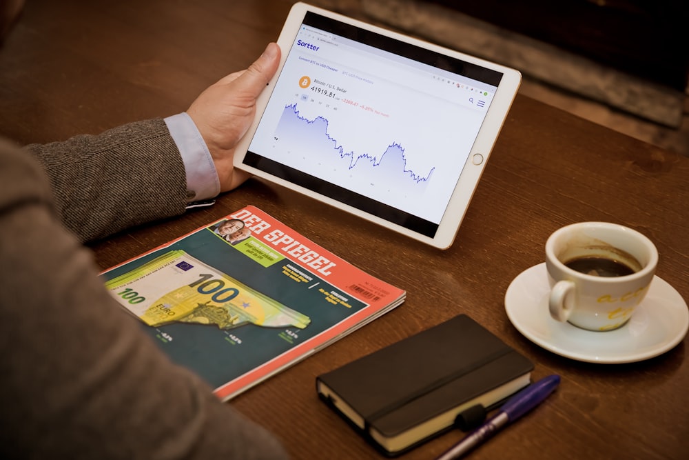 a person sitting at a table with a tablet and a cup of coffee