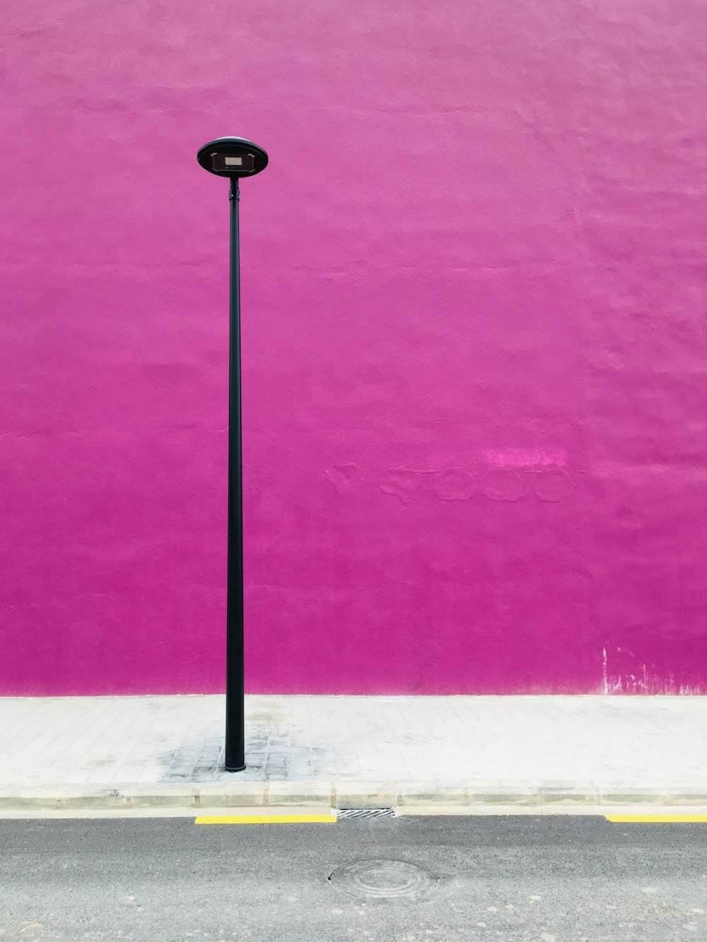 a street light in front of a pink wall