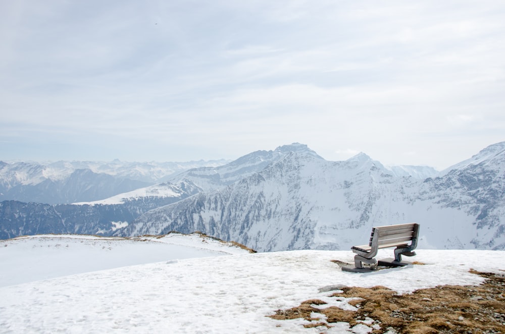 a bench sitting on top of a snow covered slope