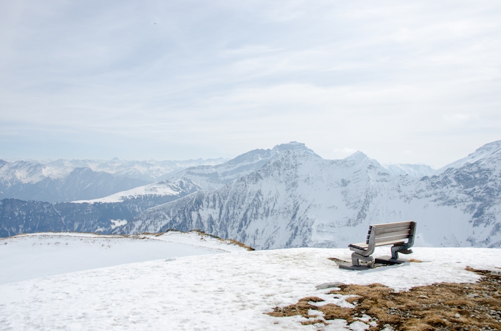 um banco sentado em cima de uma encosta coberta de neve