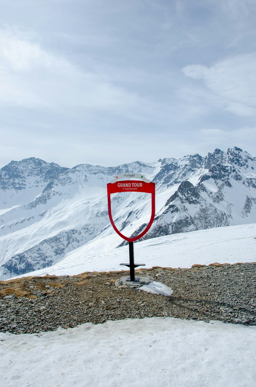 a red sign on top of a snow covered mountain