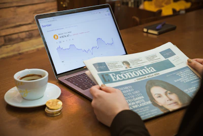 a person reading a newspaper next to a cup of coffee