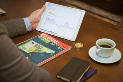 a person sitting at a table with a tablet and a cup of coffee