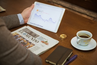 a person sitting at a table with a tablet and a cup of coffee
