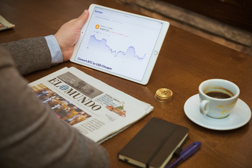 a person sitting at a table with a tablet and a cup of coffee