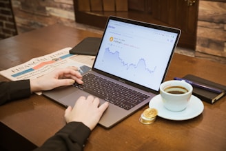 a person using a laptop on a table with a cup of coffee
