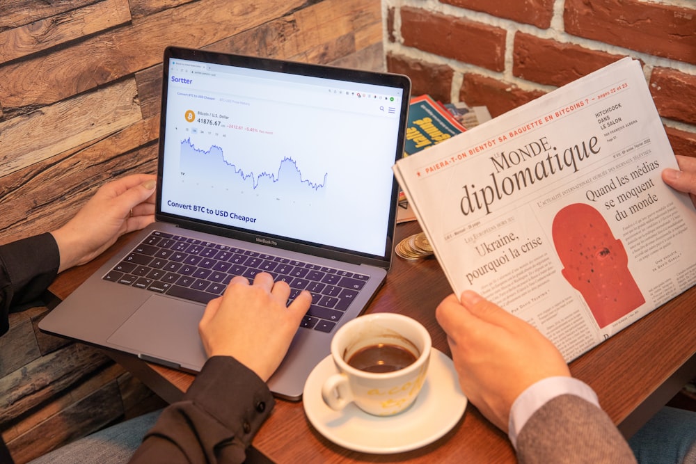 uma pessoa sentada em uma mesa com um laptop e uma xícara de café