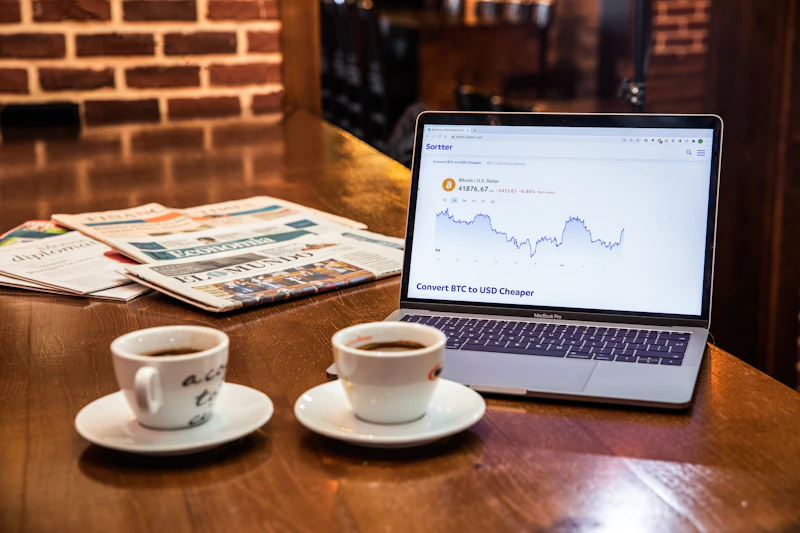 Laptop displaying financial charts next to coffee