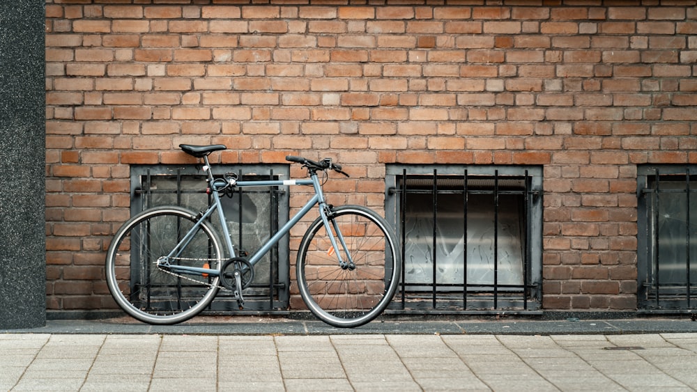 a bicycle parked next to a brick wall