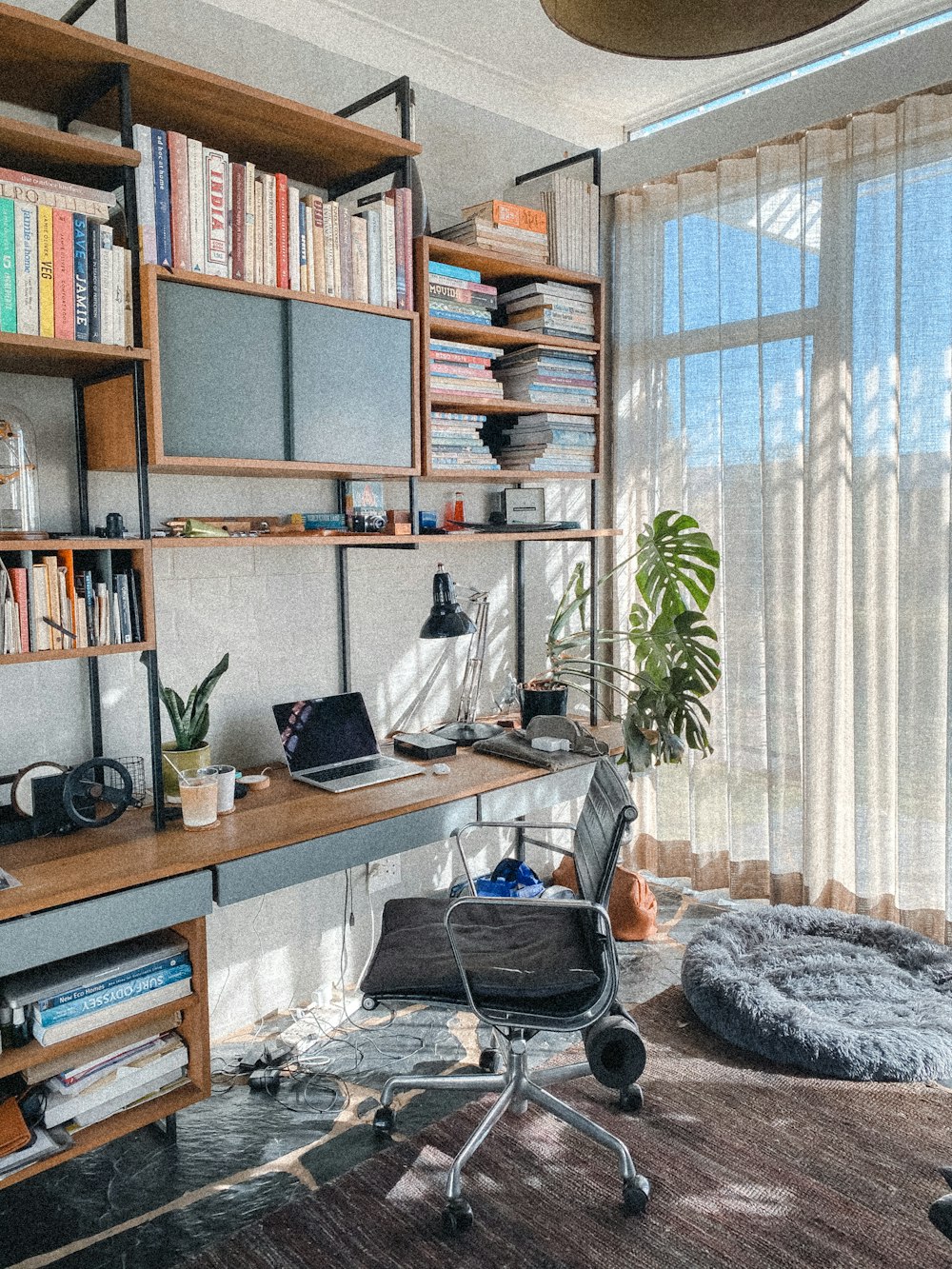 a room with a desk, chair and bookshelf