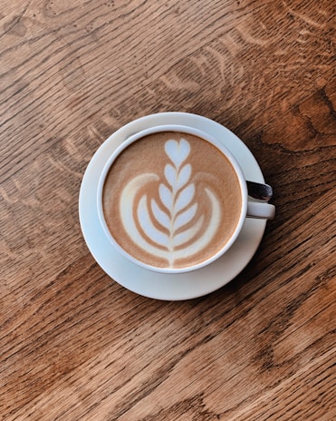 A beautifully crafted latte with intricate foam art served on a wooden table.