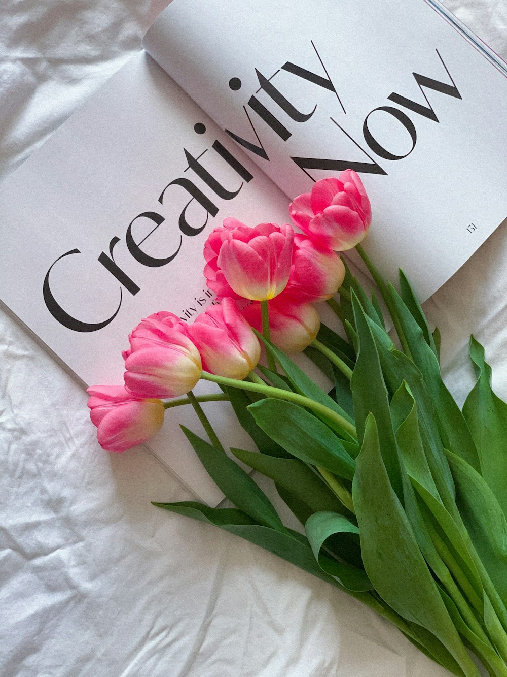 a bouquet of pink tulips sitting on top of a book