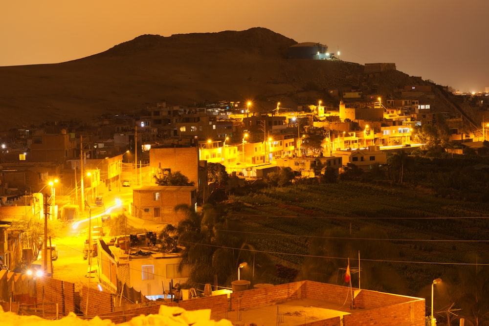 a city lit up at night with a hill in the background