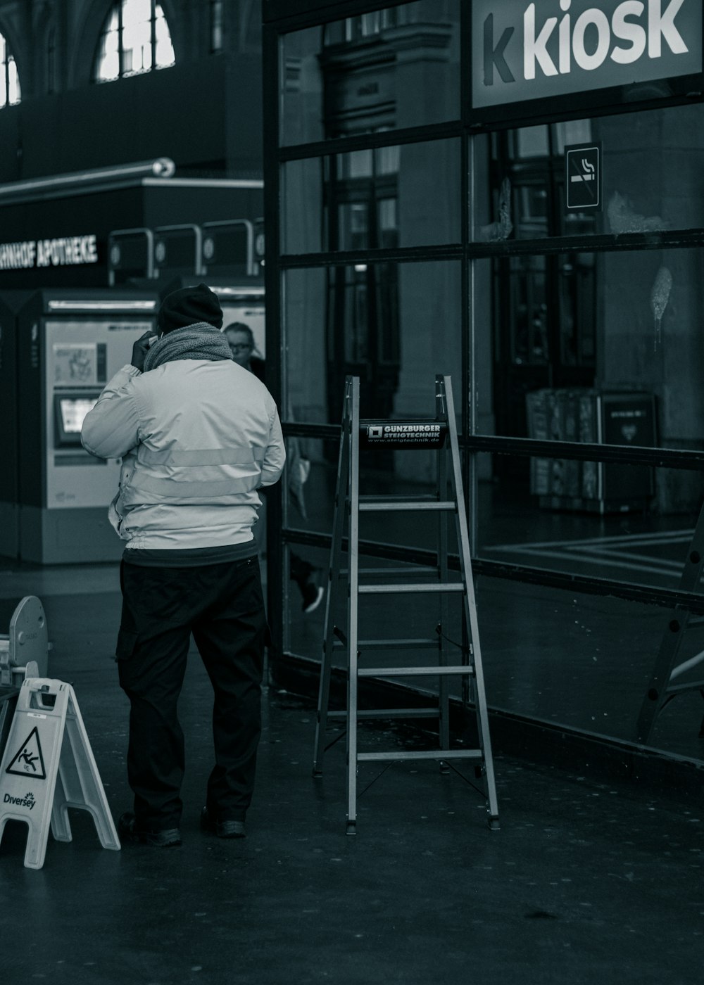 a man standing in front of a kiosk talking on a phone