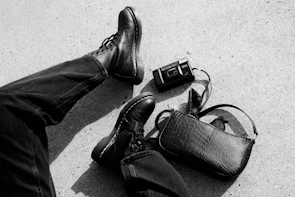 Close-up of trendy leather boots paired with a chic handbag on a rustic wooden floor
