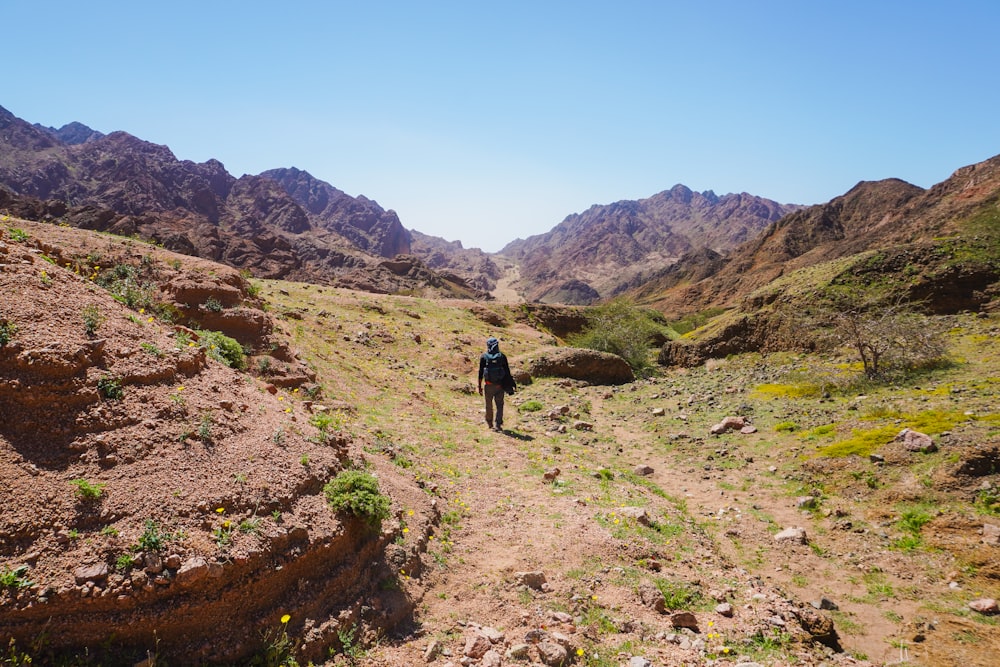 a man hiking up a trail in the mountains