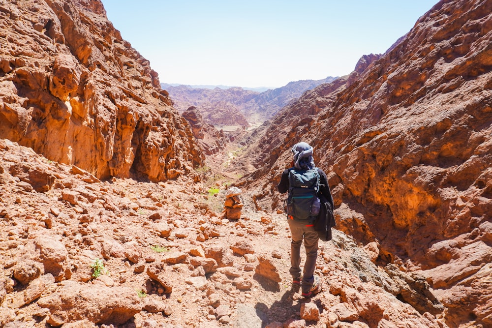 a person with a backpack hiking through a canyon