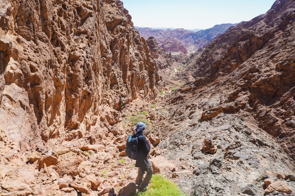 a man hiking through a canyon in the mountains