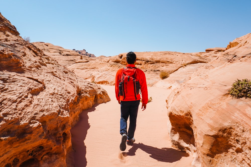 a man in a red jacket is walking through the desert