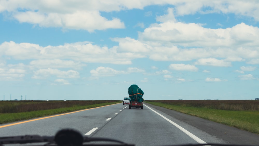 a truck driving down a highway with a person in the back of it