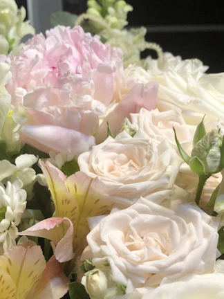 Close-up of a lush bouquet bursting with fresh roses and lilies in soft pastel tones.
