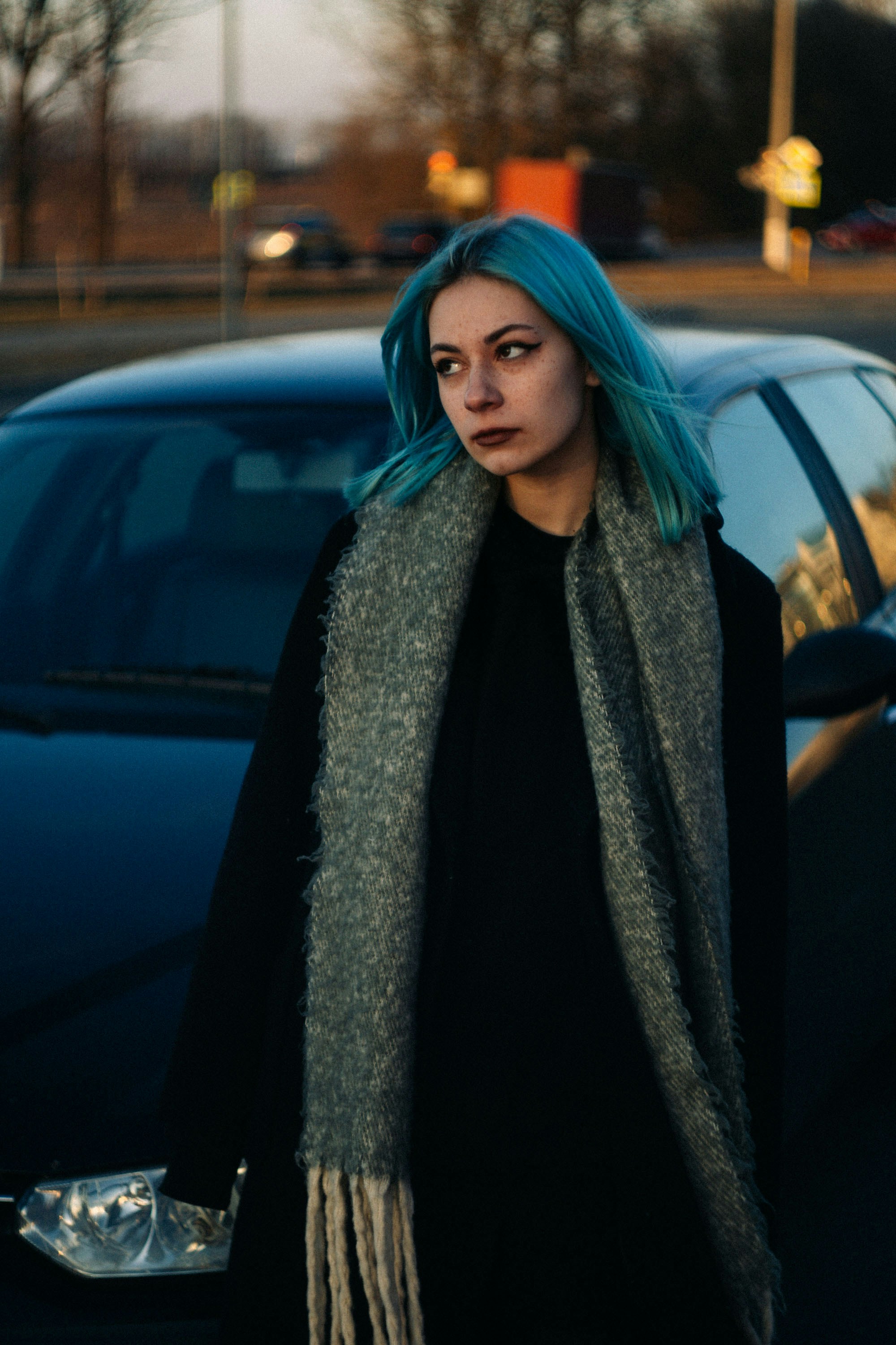 Eine Frau mit blauen Haaren steht vor einem Auto