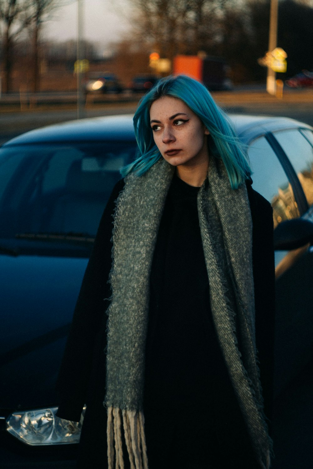 a woman with blue hair is standing in front of a car