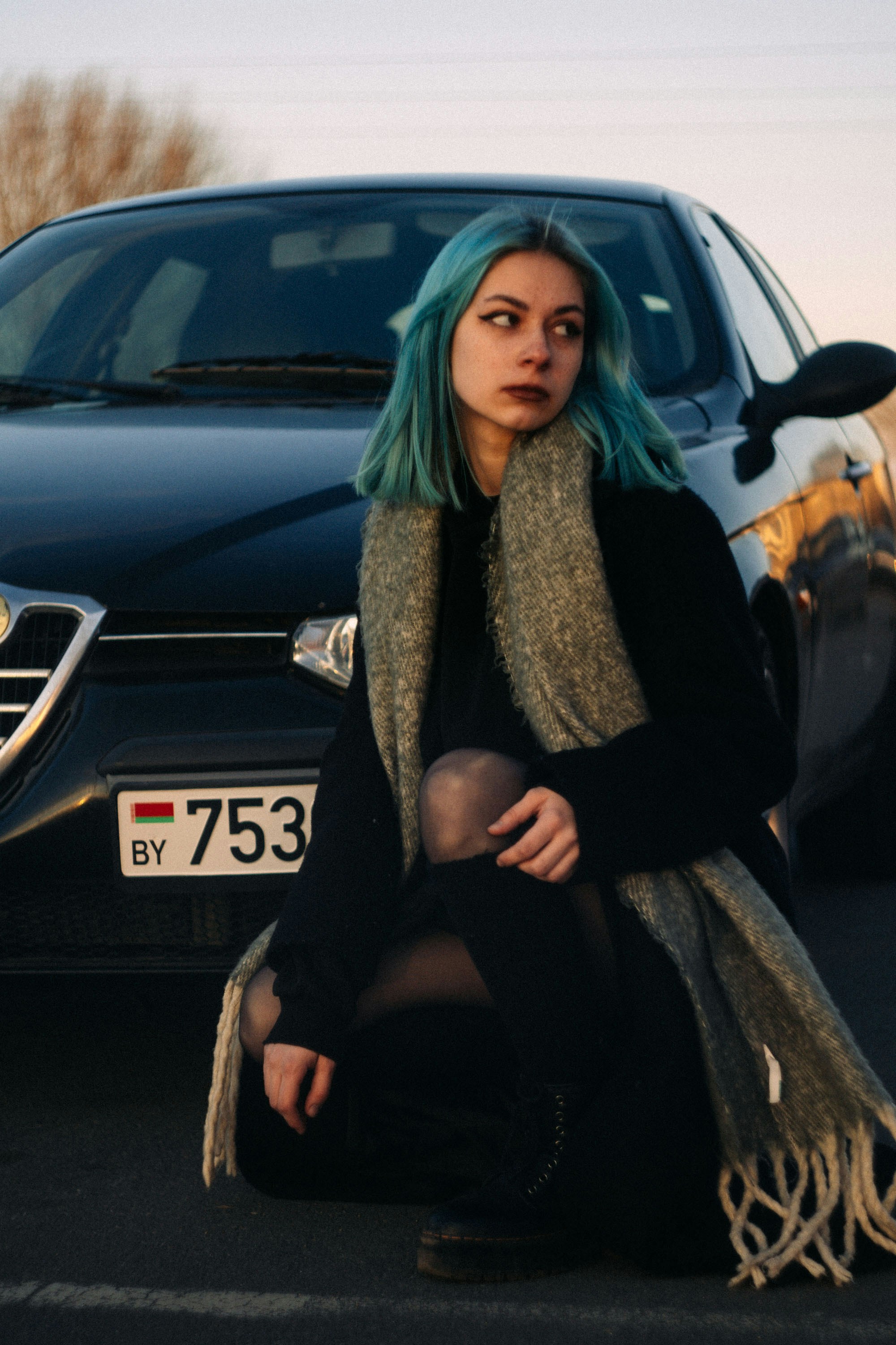 Eine Frau mit blauen Haaren sitzt vor einem Auto