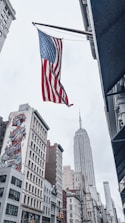 an american flag flying in the air over a city