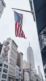 an american flag flying in the air over a city