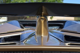 Close-up of a sleek, glossy car spoiler catching the sunlight on a winding road.
