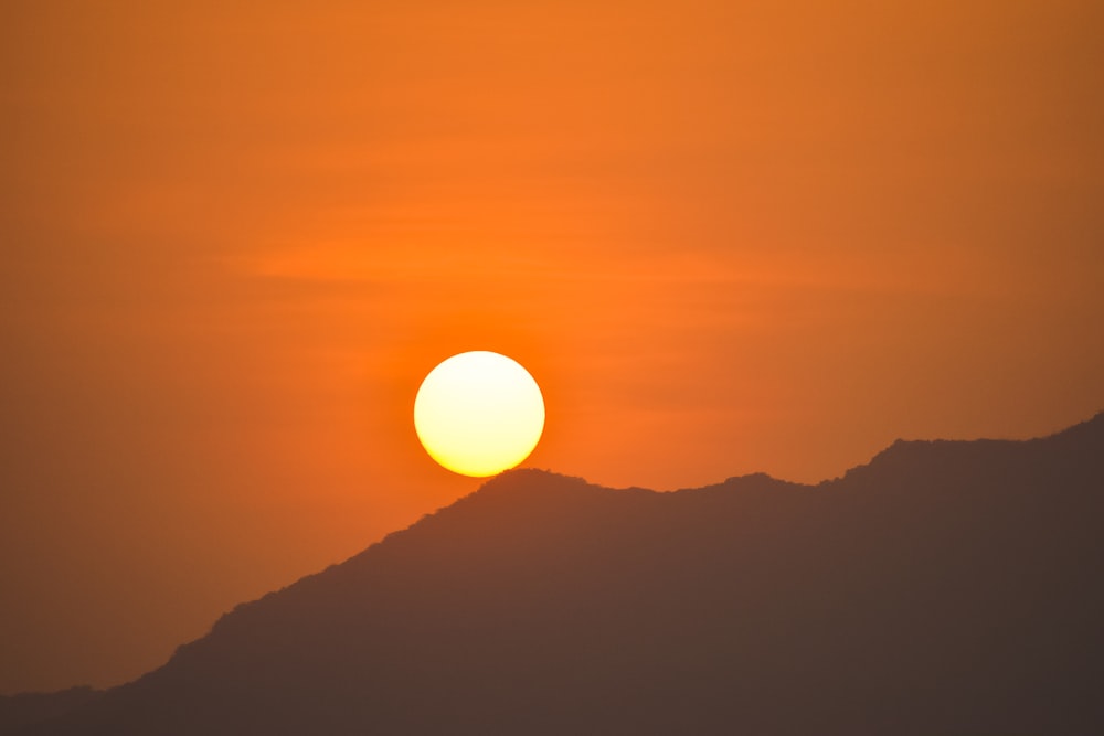 the sun is setting over a mountain range