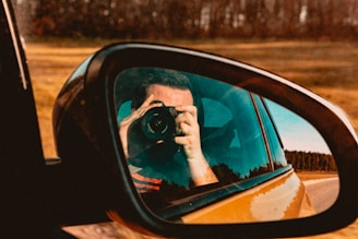 a man taking a picture of himself in the side mirror of a car