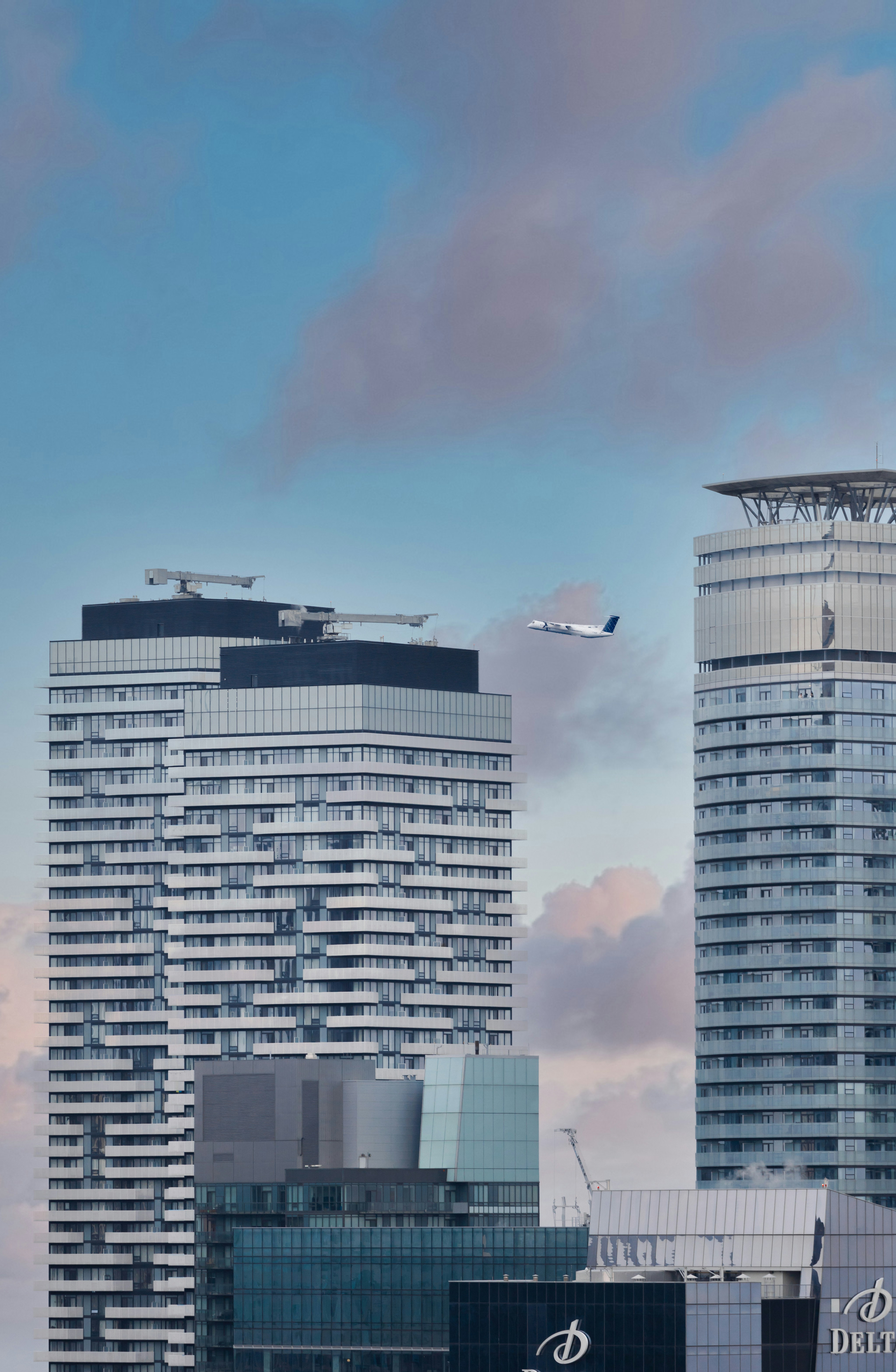 Ein paar hohe Gebäude mit einem Flugzeug, das am Himmel fliegt