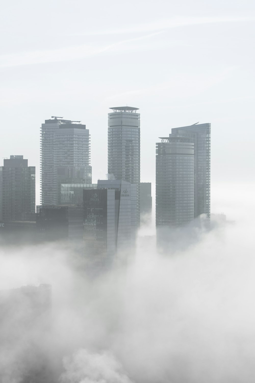 a city in the fog with skyscrapers in the background