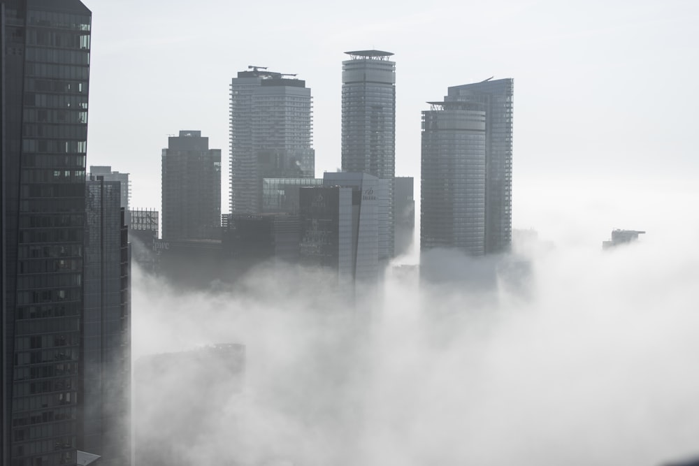 a city in the fog with skyscrapers in the background