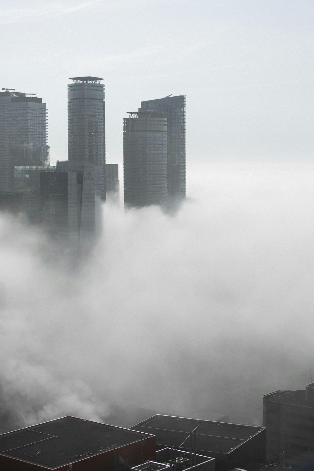 a city in the fog with skyscrapers in the background