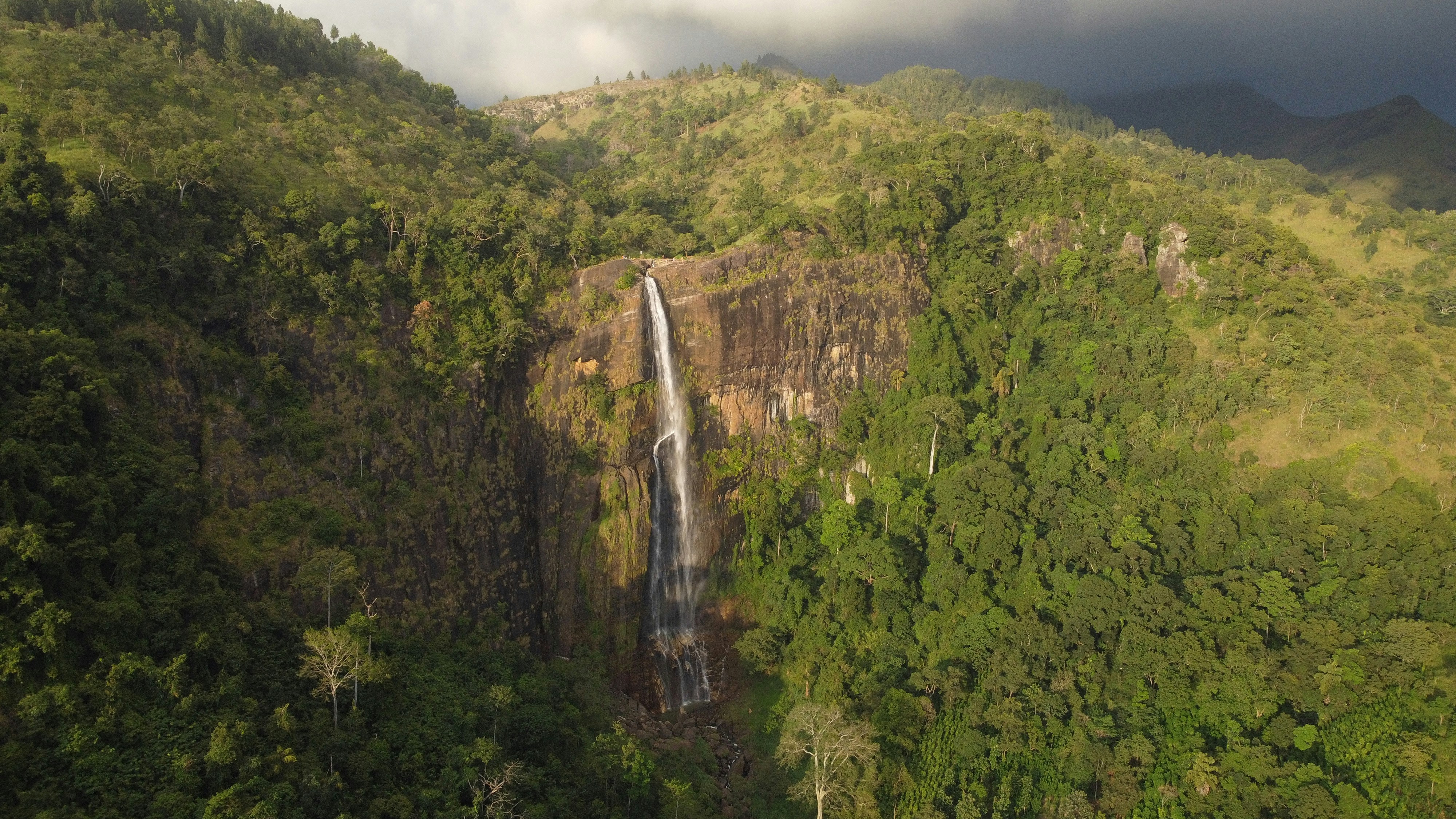 a large waterfall in the middle of a lush green forest