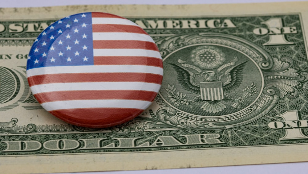 Un botón con la bandera estadounidense encima de un billete de un dólar